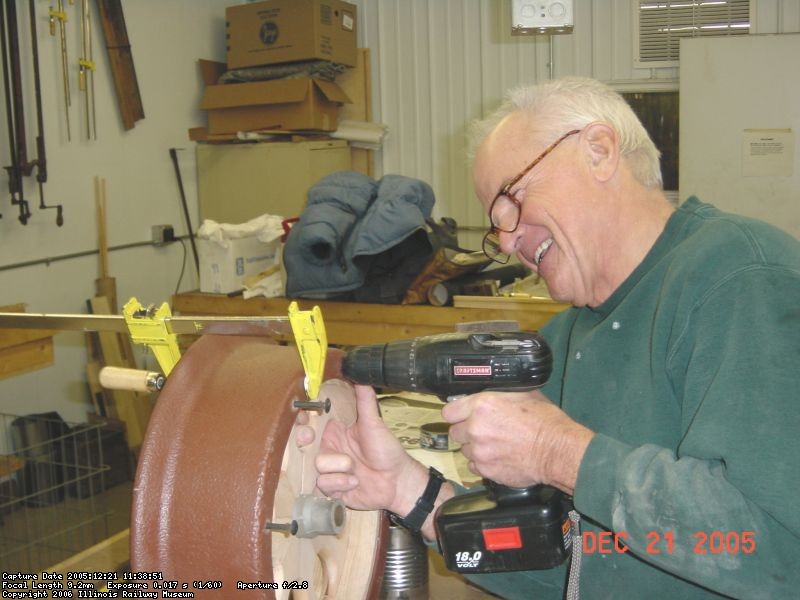 12.21.05 - DICK CUBBAGE IS DRILLING HOLES FOR THE BOLTS THAT SECURE THE SPOKES AND ARC SEGMENT TO THE HUB.