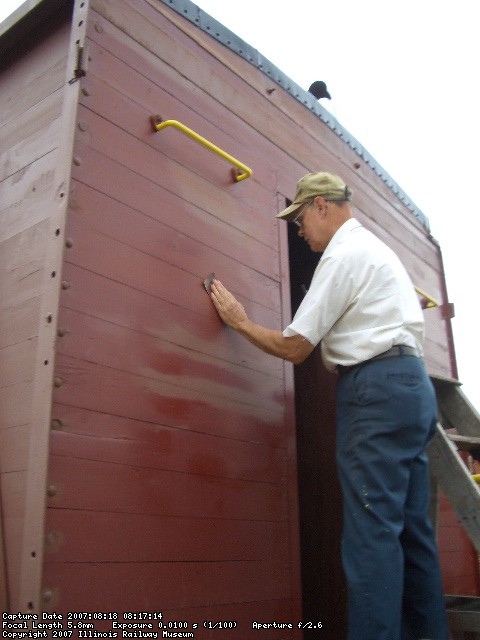08.18.07 - VICTOR HUMPHREYS SANDS THE PRIMER, WHICH WAS APPLIED WHERE FINISH PAINT HAD PEELED, PRIOR TO APPLYING THE SECOND COAT OF FINSIH PAINT TO THE A END OF THE CABOOSE WALL.