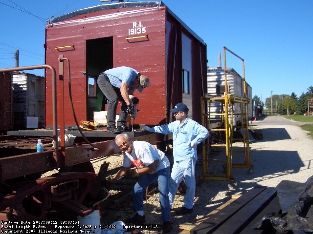 09.12.07 - DICK CUBBAGE IS REPACKING THE R2 JOURNAL BOX.  THE ENTIRE B TRUCK WAS REPACKED TODAY.  THE BL SILL STEPS WERE ALSO REMOVED.  JOHN FAULHABER DRILLS A HOLE TO SECURE THE DECKING, WHILE SON JAMES FAULHABER WAITS TO THE RIGHT TO APPLY A TIMBER BOLT.  KIRK, JOHN AND JAMES APPLIED SEVEN MORE DECK BOARDS TODAY.