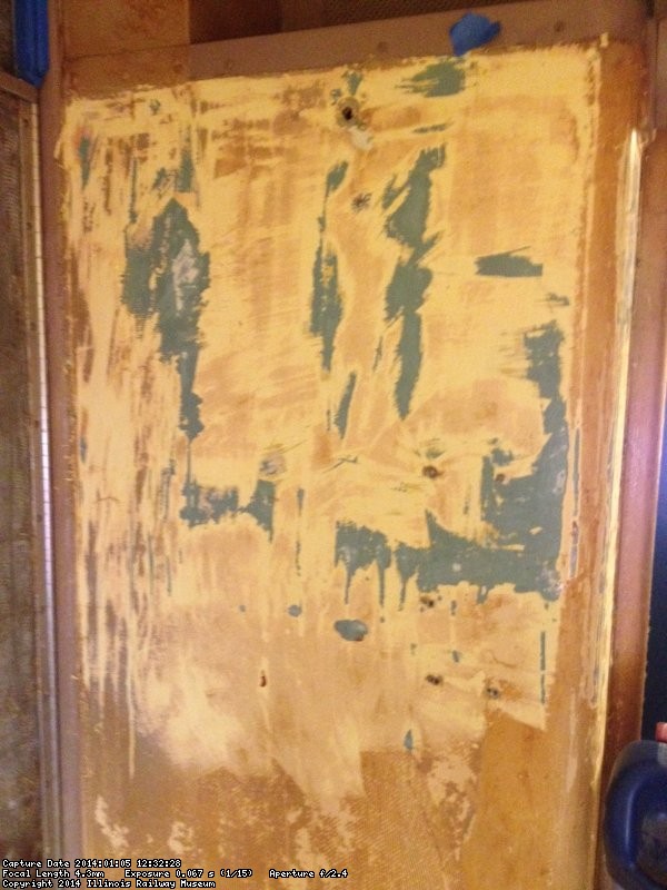 The wall in Bedroom F by the divider door being stripped of the glue and paint.