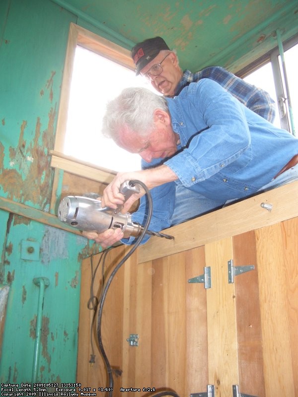 05.27.09 - BILL IS DRILLING A HOLE FOR A GRAB IRON INTO THE FACE OF A NEWLY CONSTRUCTED CABINET, USED TO CLIMB INTO THE CUPOLA.