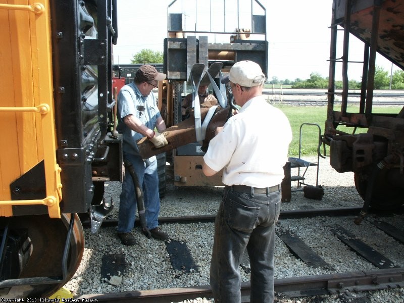 05.26.10 - VICTOR HUMPHREYS AND JOHN FAULHABER ARE REINSTALLNG THE COUPLER, WITH GERRY DETTLOFF RUNNING THE SKID LOADER, AFTER REPAIRS TO THE STRIKER AND COUPLER CARRIER. 