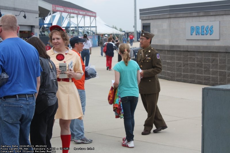 Rebecca in her Rockford Peaches uniform and one of the reenactors in his dress uniform hand out brochures to the WWII event.
