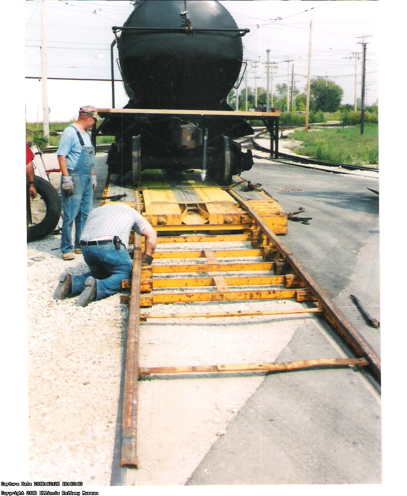 PETE GALAYDA WATCHES THE DRIVER ATTACH THE UNLOADING RAMPS TO THE TRAILER.  THE ENDS OF THE RAMPS GO ONTO THE TRACK.
