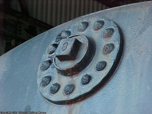 A PLUGGED THREADED FLANGE WHICH IS ORIGINAL TO THE CAR.  IT WAS USED TO LOAD HEATER COIL PIPLE INTO THE TANK, ALLOWING LONGER SECTIONS OF PIPE TO BE USED.