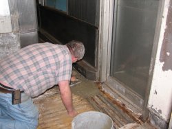 Mike applies the first batch of concrete to the area in front of the door. 