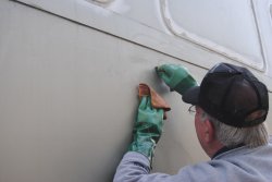 Close-up of Kevin working to remove adhesive on the 1st Exhibit Car exterior