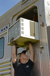 Andy Townsend holding up an AC unit during installation - Photo by Jon Habegger 