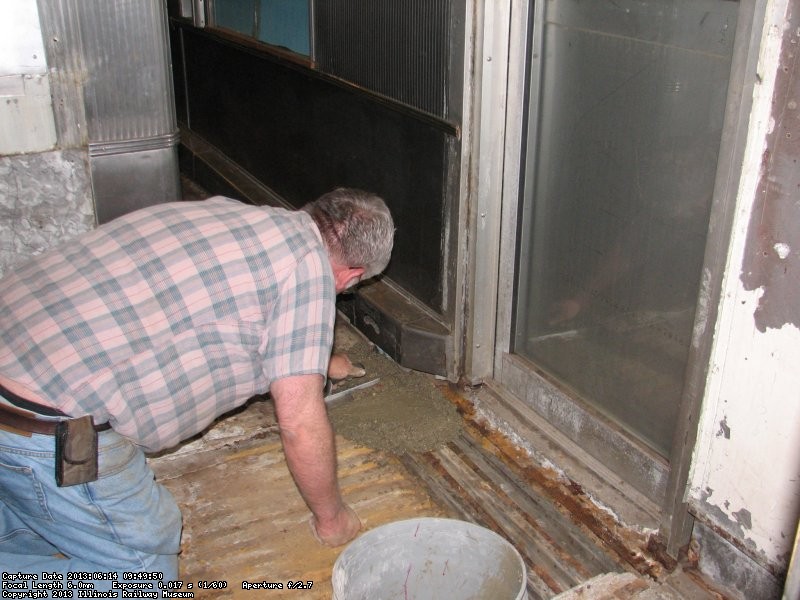 Mike applies the first batch of concrete to the area in front of the door. 
