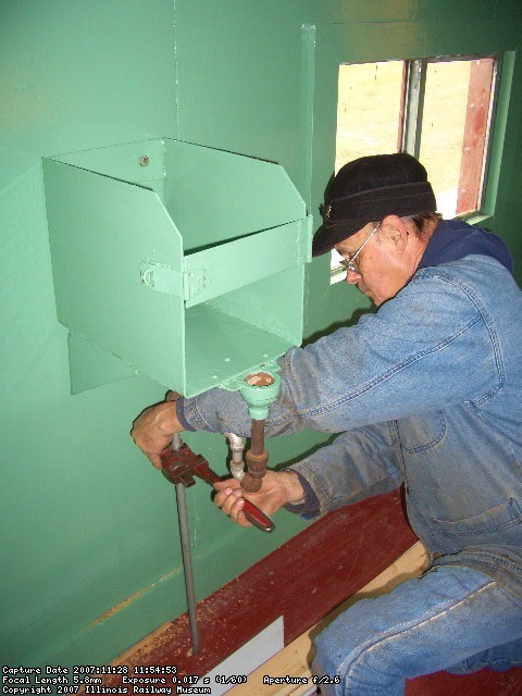 11.28.07 - VICTOR HUMPHREYS IS TIGHTENING THE DRAIN PIPES FOR THE OVERFLOW OF THE DRINKING WATER DISPENSER.