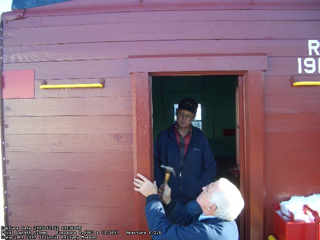 12.12.07 - KIRK WARNER APPLIES THE DOOR FRAME TRIM PIECES TO THE A END AS VICTOR HUMPHREYS LOOKS ON.  BOTH THE A AND B END DOOR TRIM PIECES WERE INSTALLED TODAY.