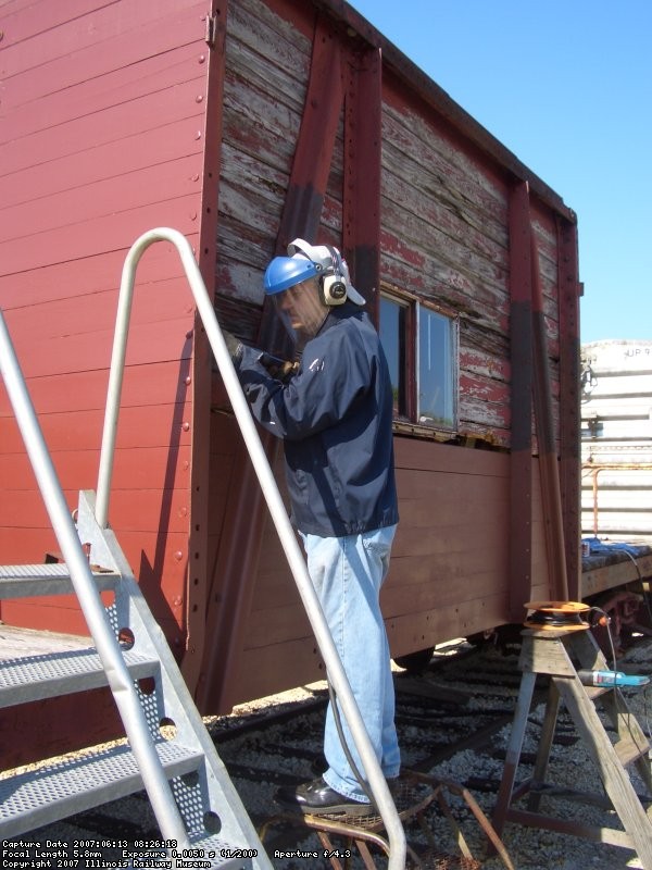 06.13.07 -KIRK WARNER AND JOHN FAULHABER HAVE NEEDLE CHIPPED THE EXTERIOR BRACES FOR THE NEXT SIX ROWS OF SIDING TO BE APPLIED.  IN THE PHOTO, JOHN IS FINISHING THE BRACES HE WORKED ON.