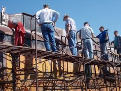 The team gathered on the scaffold to examine the early sandblasting results - Photo by Jane Pomazal