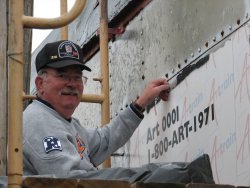 Kevin Kriebs smiles while peeling decals from the second Exhibit Car