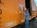 08.02.09 - BOB KUTELLA IS CHECKING THE FIT FOR THE NEXT STENCIL TO BE CUT. THE BEVELED SIDING MAKES THIS ONE A DIFFICULT STENCIL TO APPLY. ONE OTHER STENCIL IS CUT AND IS IN PLACE, READY FOR PAINT.  THE DOOR IS OPEN SO THAT WE CAN GET INSIDE TO TAKE MEASUREMENTS FOR THE INTERIOR DIMENSION STENCILS.