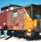 09.11.04 - OVER ONE HALF OF THE LEFT SIDE OF THE CAR HAS NOW BEEN PRIMED.  KIRK WARNER AND VICTOR HUMPHREYS (PARTILLY CUT OUT OF THE PHOTO) DISCUSS THE RESTORATION.  PART OF THE LEFT SIDE OF THE IS NEEDLE CHIPPED; HOWEVER, IT IS NOT WIRE WHEELED OR PRIMED.