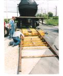 PETE GALAYDA WATCHES THE DRIVER ATTACH THE UNLOADING RAMPS TO THE TRAILER.  THE ENDS OF THE RAMPS GO ONTO THE TRACK.